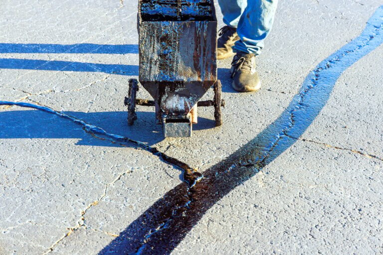 An asphalt patcher performs coated filling asphalt cracks sealing bitumen emulsion road