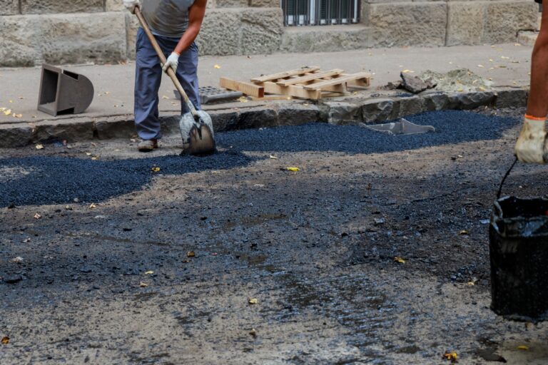 At road constructio workers team throw asphalt with shovels n