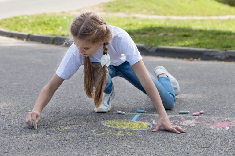 Children's hand draws with crayons on the asphalt