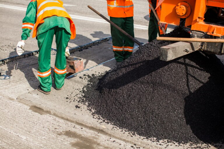 The man working asphalt pouring tar for road repair