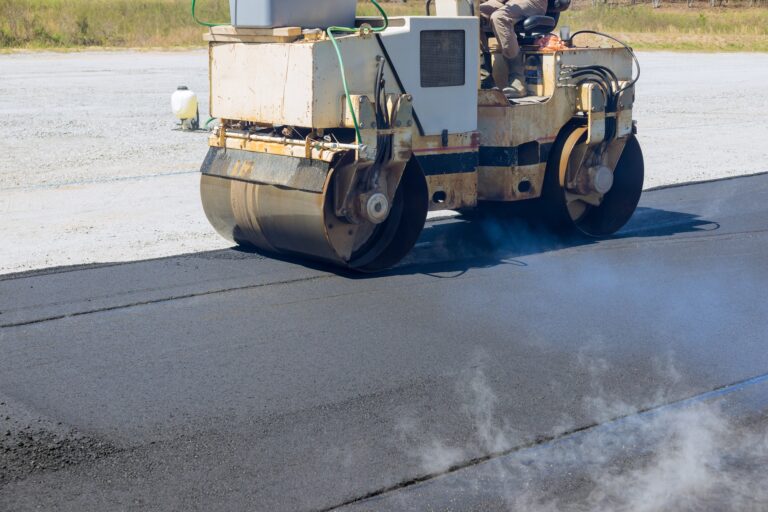 Worker uses asphalt roller is laying asphalt to road