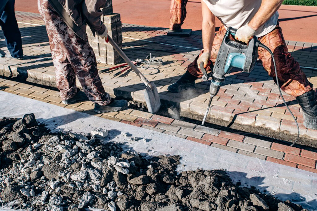 Workers laid paving slabs. Two workers lay paving slabs.