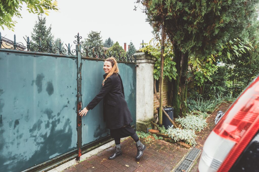 Young woman closing driveway gates
