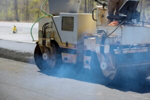 A worker uses an asphalt roller to lay asphalt on new road