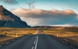 Scenic asphalt straight road with sunlight and mountain view at Iceland