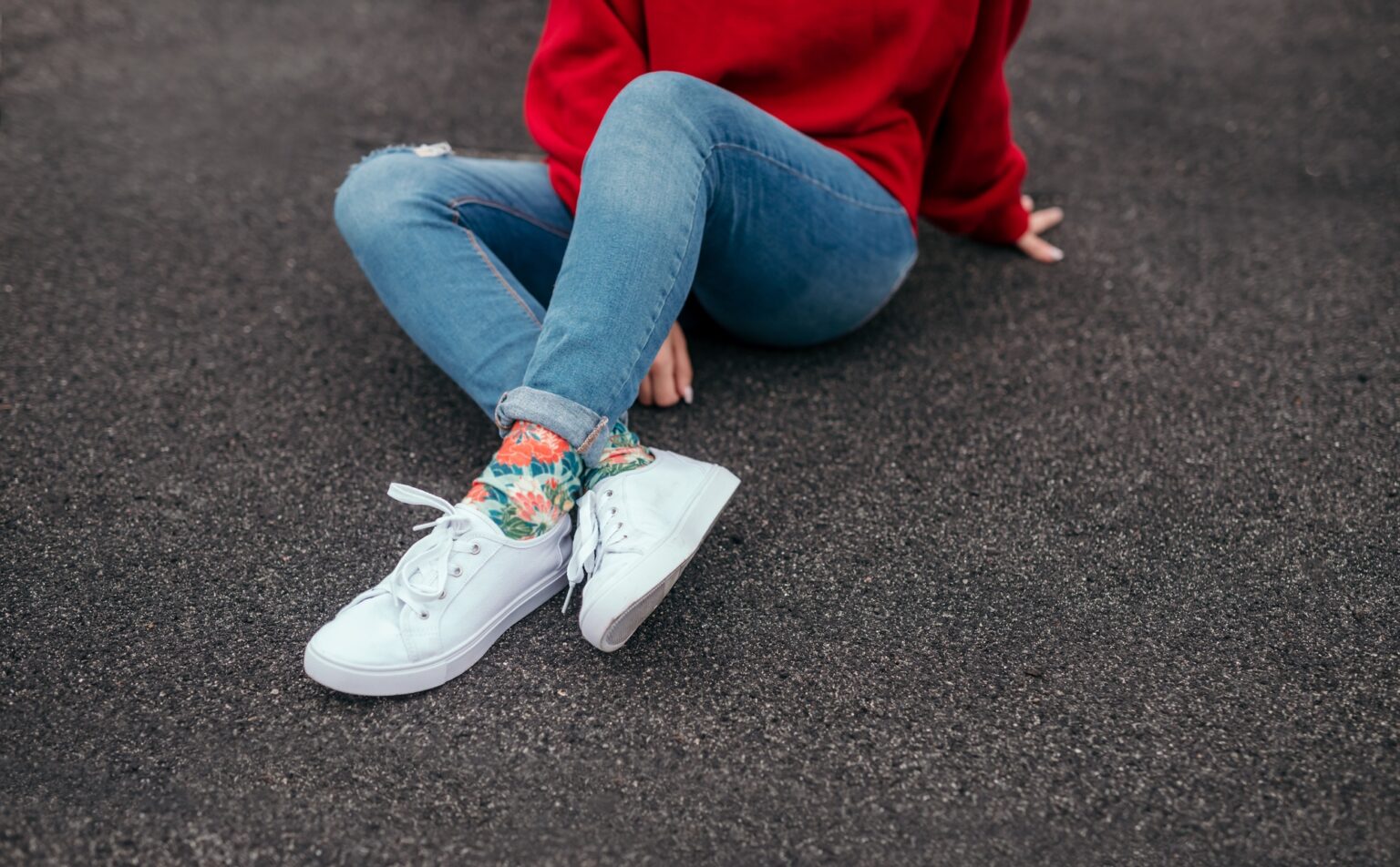 Crop hipster sitting on asphalt