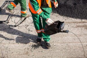 The man working asphalt pouring tar for road repair